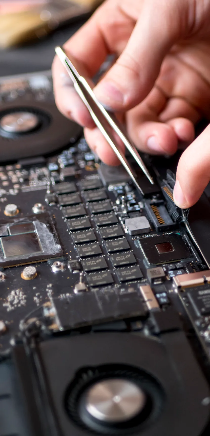 a person holding tweezers to a circuit board