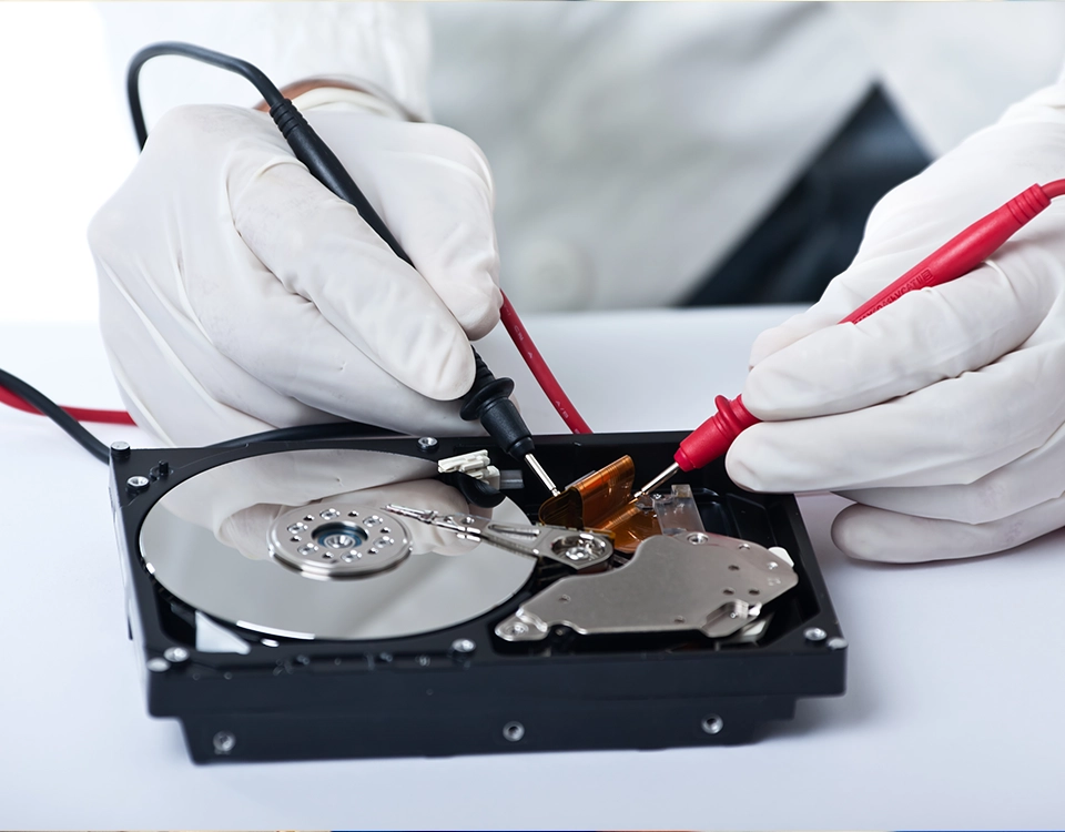 a person holding a tool to a hard drive